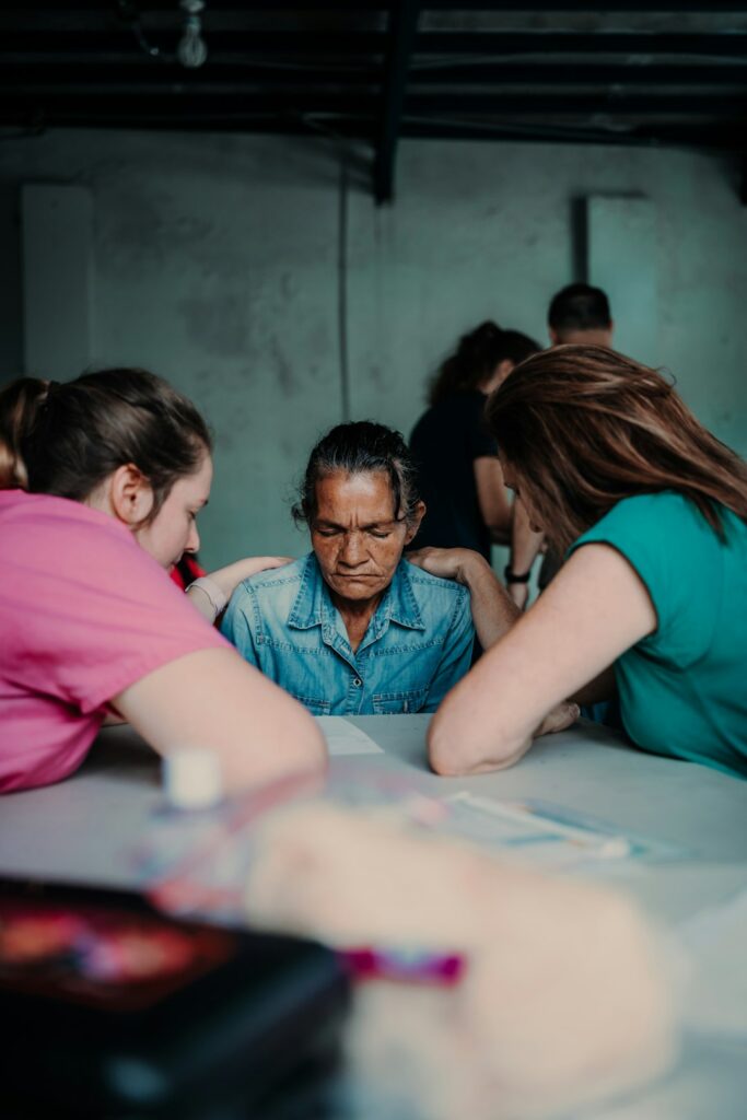 Social worker speaking with a patient and family member beside a hospital bed.